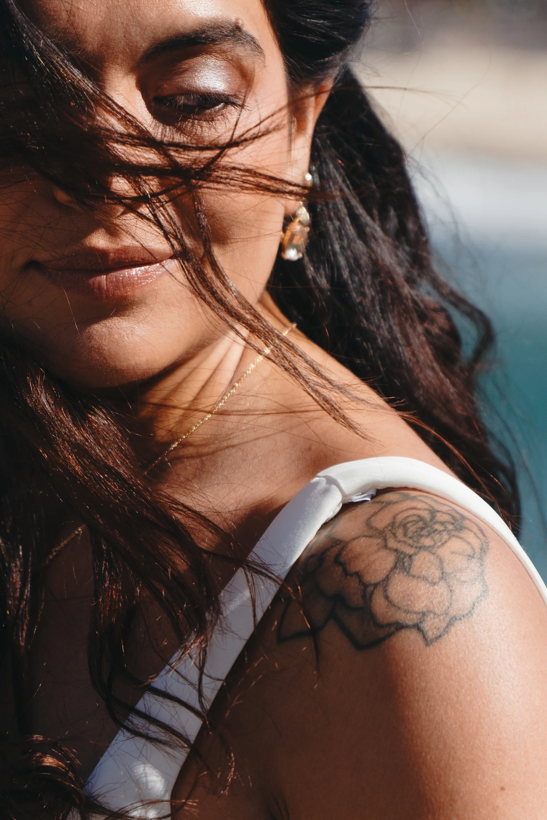 A close portrait of a bride, hair across her face in the wind.